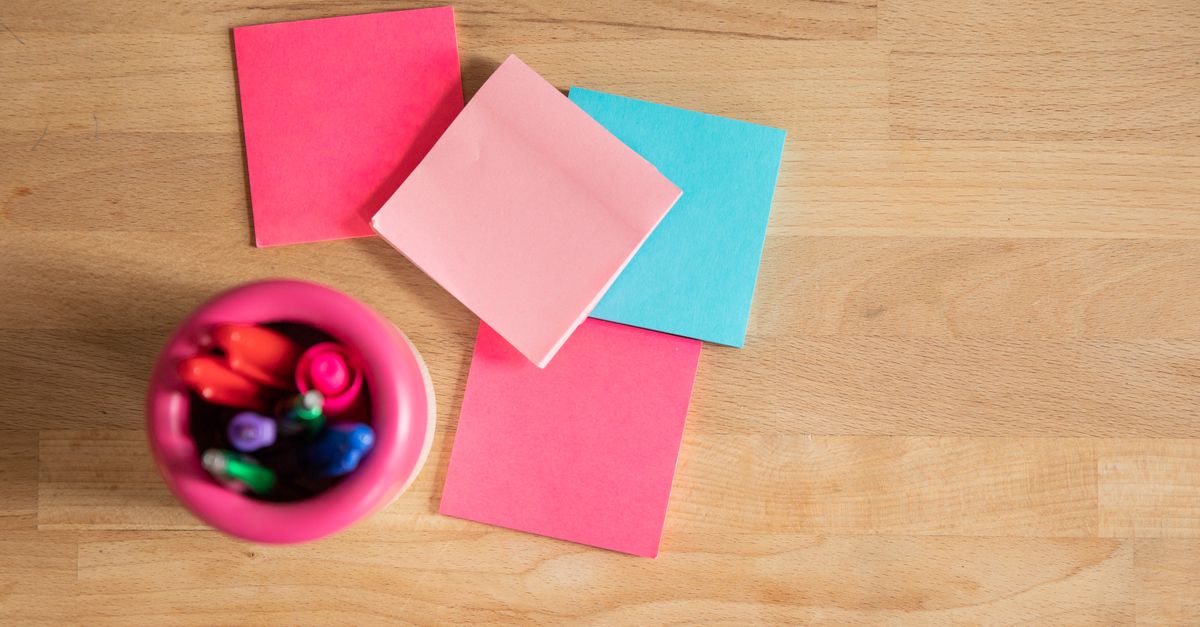 Overhead view of colorful Japanese sticky notes and pens arranged on a wooden desk